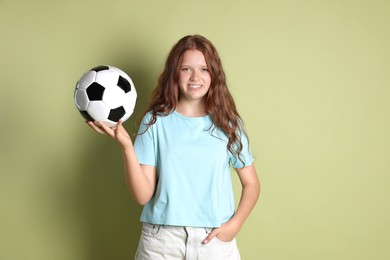 Smiling teenage girl with soccer ball on green background