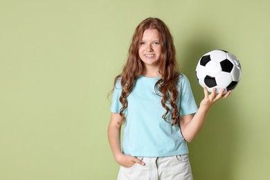 Photo of Smiling teenage girl with soccer ball on green background. Space for text