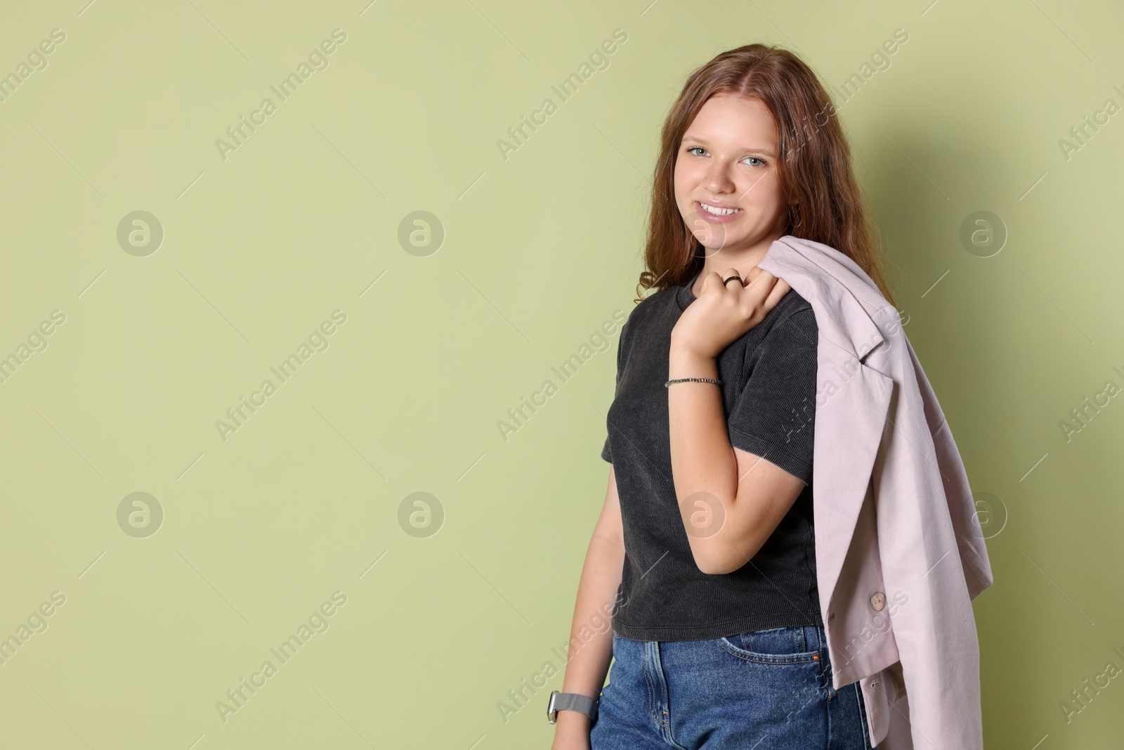 Photo of Smiling teenage girl with jacket on green background. Space for text