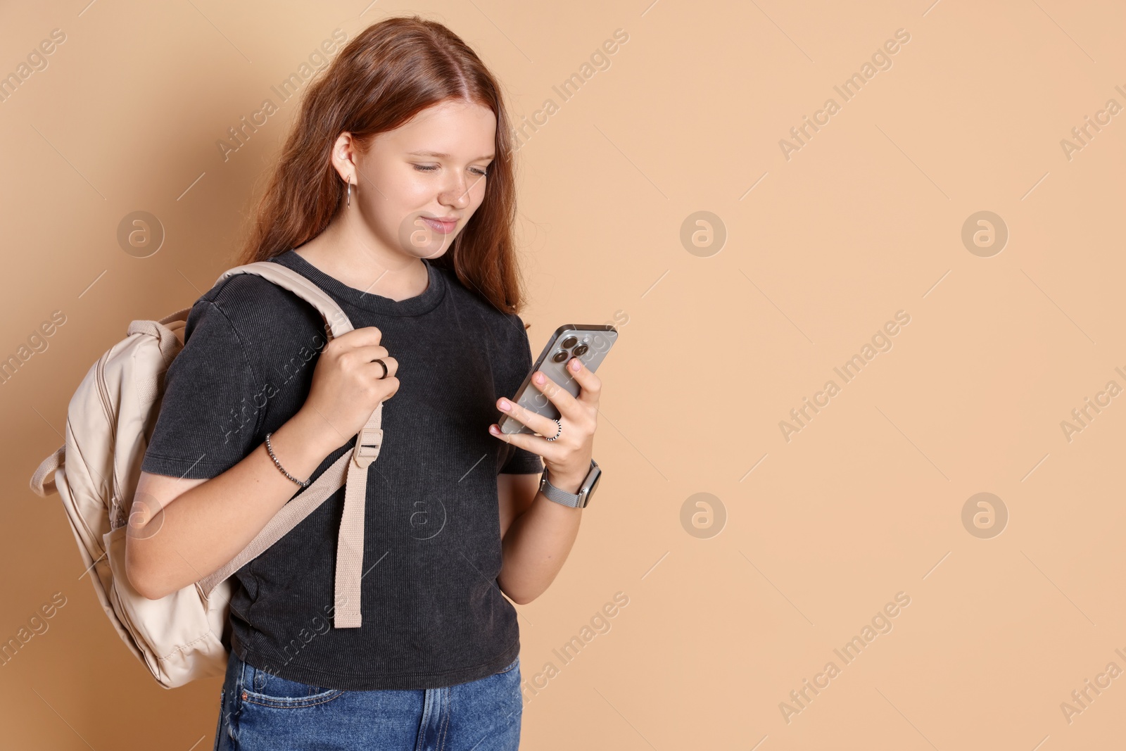 Photo of Cute teenage girl with smartphone on beige background. Space for text