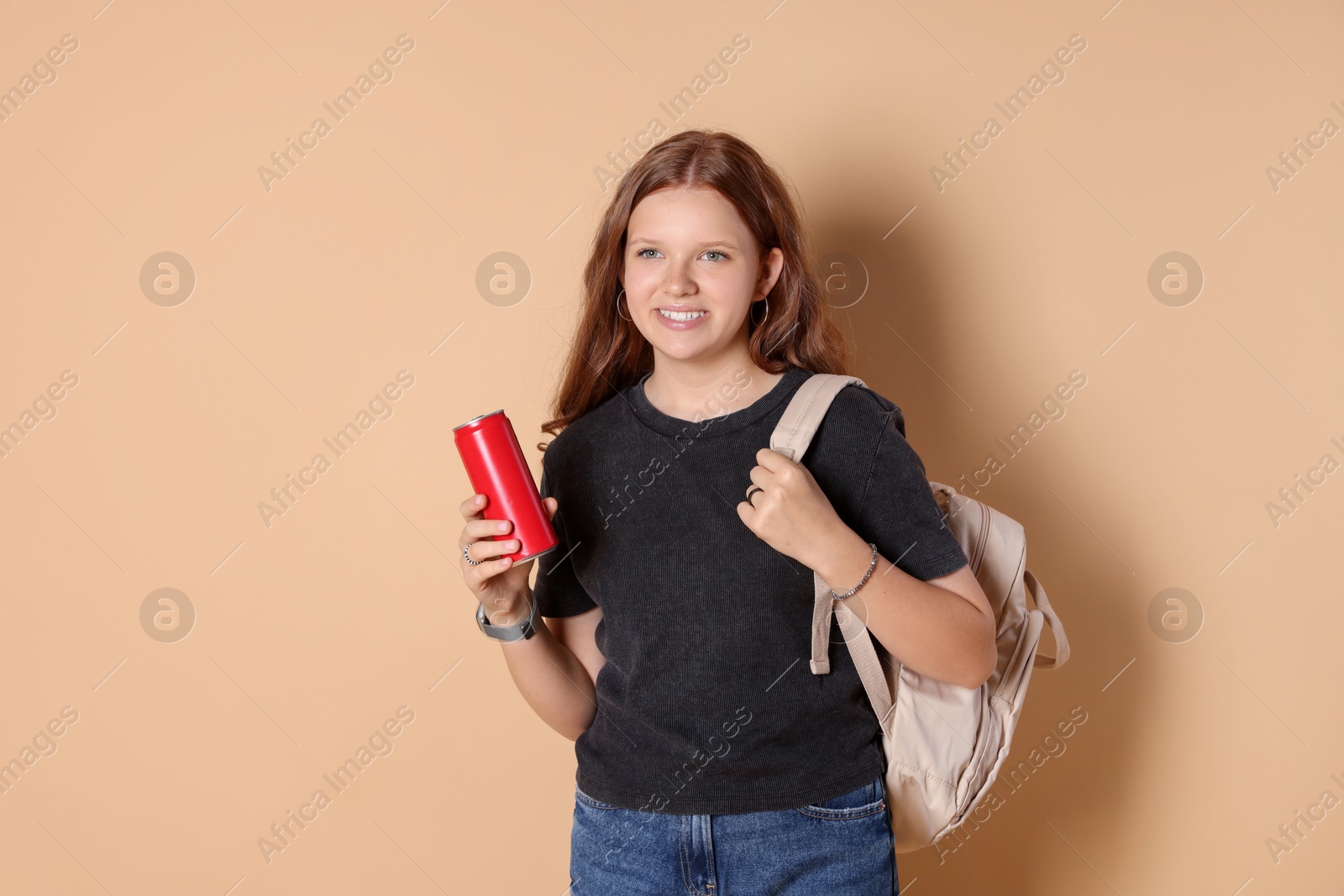 Photo of Smiling teenage girl with backpack and can on beige background. Space for text