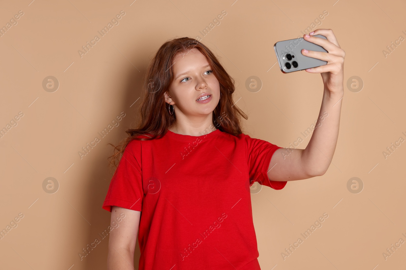 Photo of Cute teenage girl taking selfie on beige background