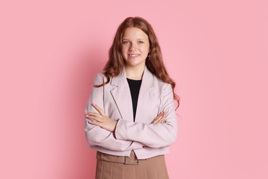 Photo of Smiling teenage girl with crossed arms on pink background