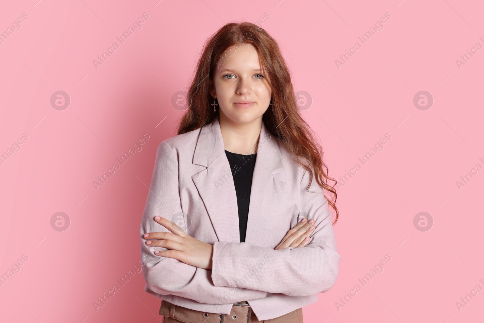 Photo of Cute teenage girl with crossed arms on pink background