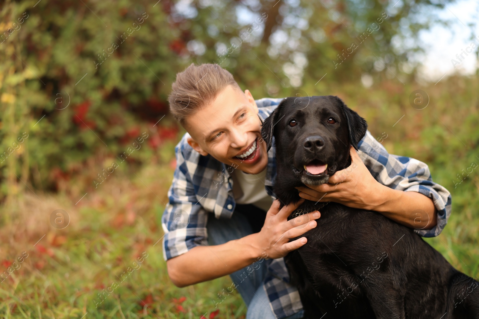 Photo of Smiling man hugging cute dog outdoors on autumn day