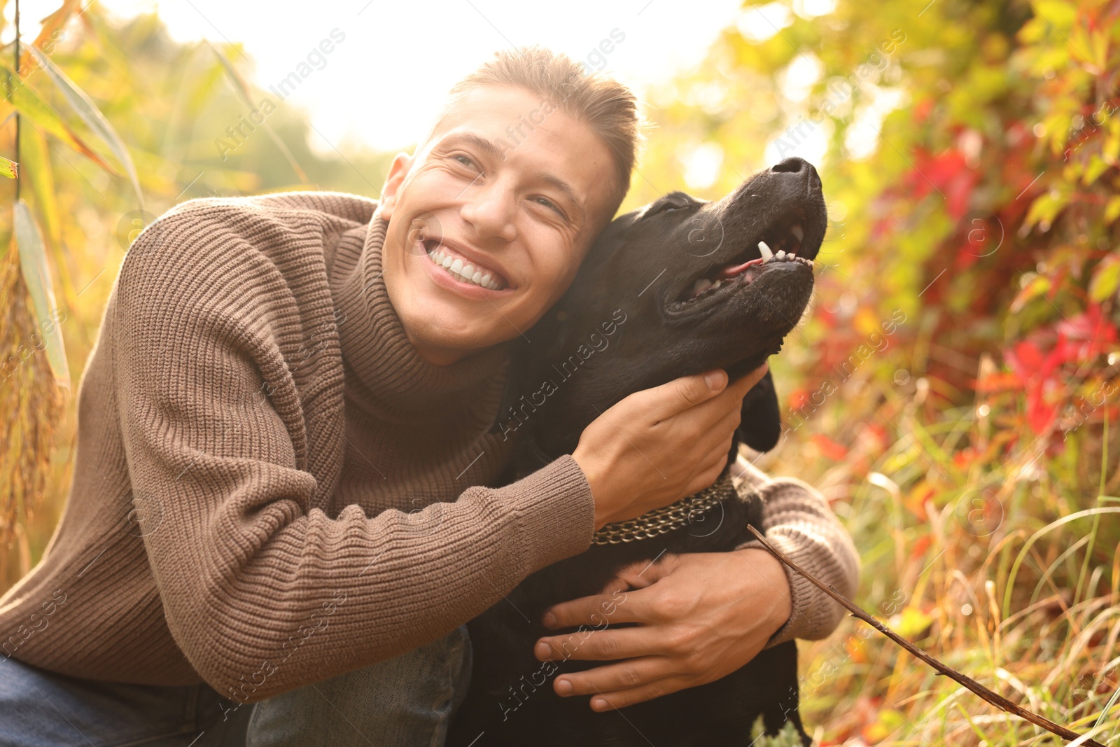 Photo of Smiling man hugging cute dog outdoors on autumn day