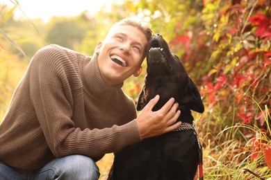 Smiling man with cute dog outdoors on autumn day