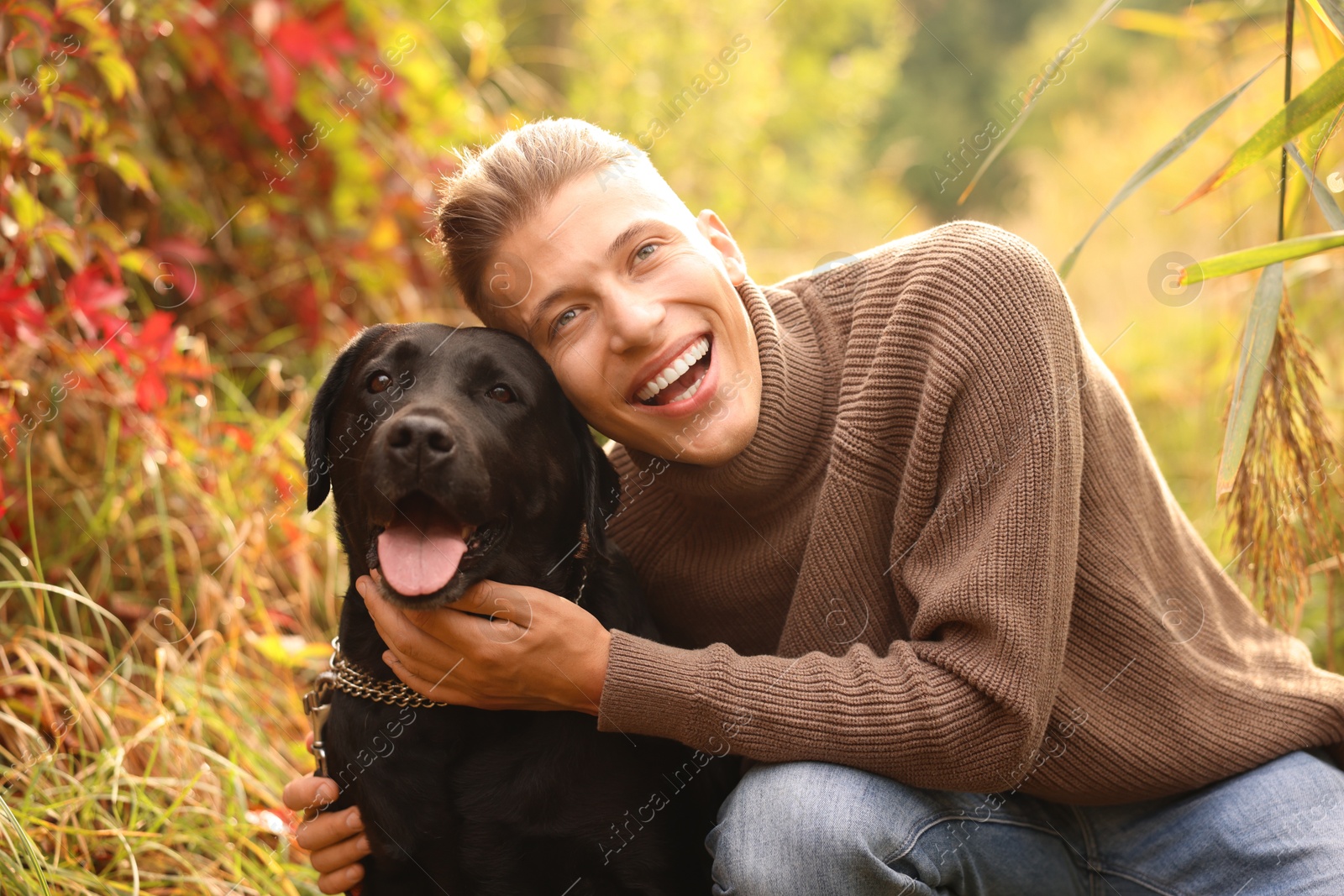 Photo of Smiling man with cute dog outdoors on autumn day