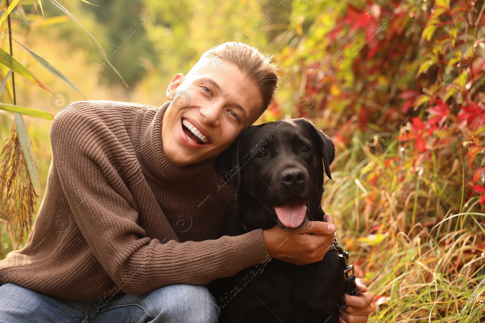 Photo of Smiling man with cute dog outdoors on autumn day