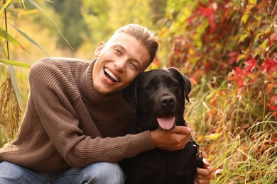 Smiling man with cute dog outdoors on autumn day