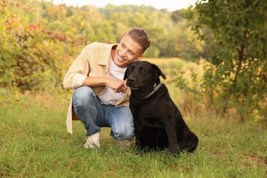 Photo of Smiling man with cute dog outdoors on autumn day