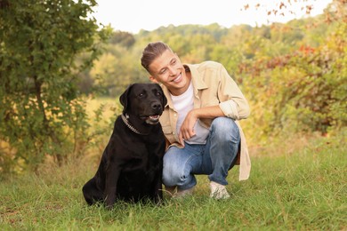 Photo of Smiling man with cute dog outdoors on autumn day