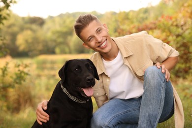 Photo of Smiling man with cute dog outdoors on autumn day