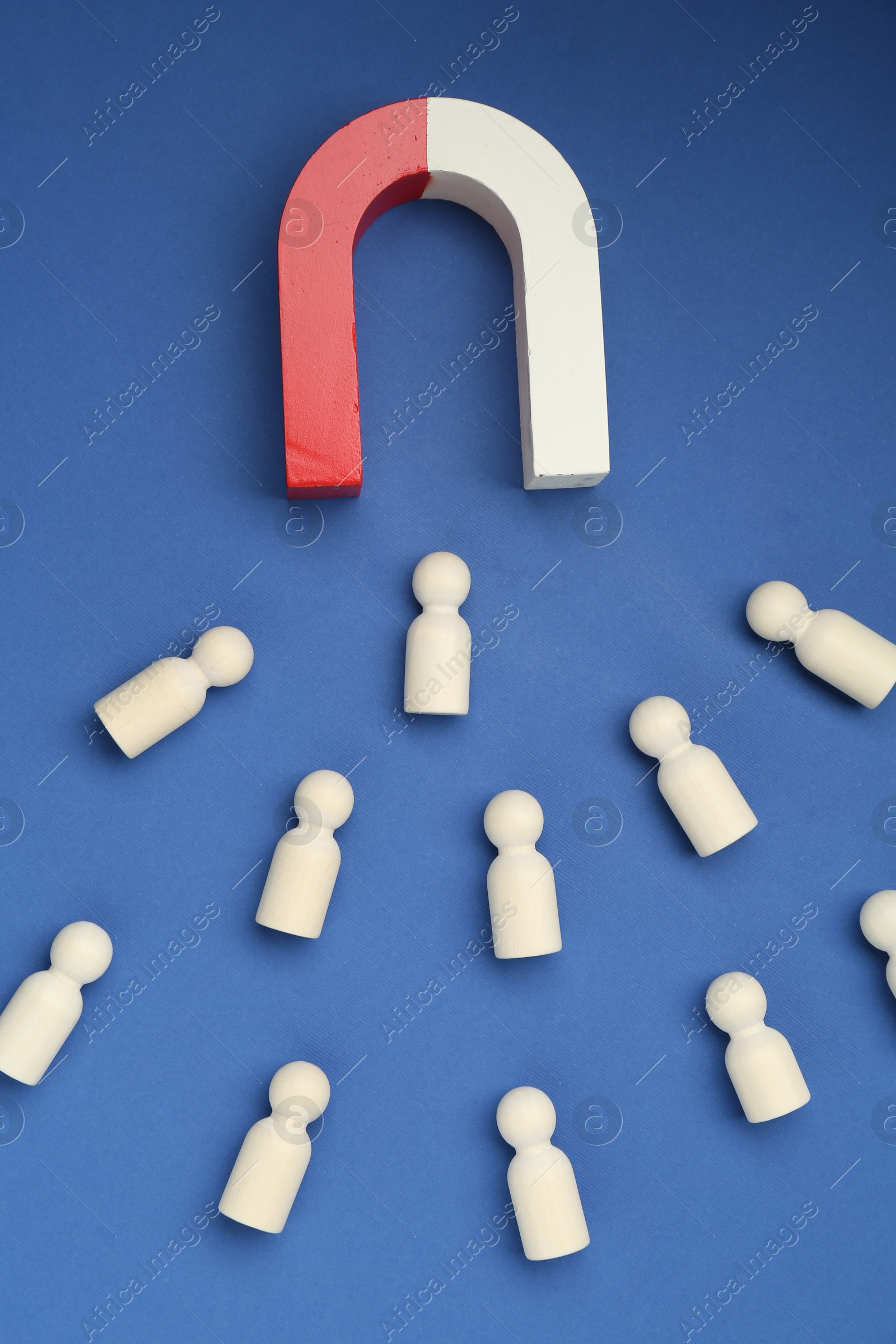 Photo of Magnet attracting human figures on blue background, flat lay