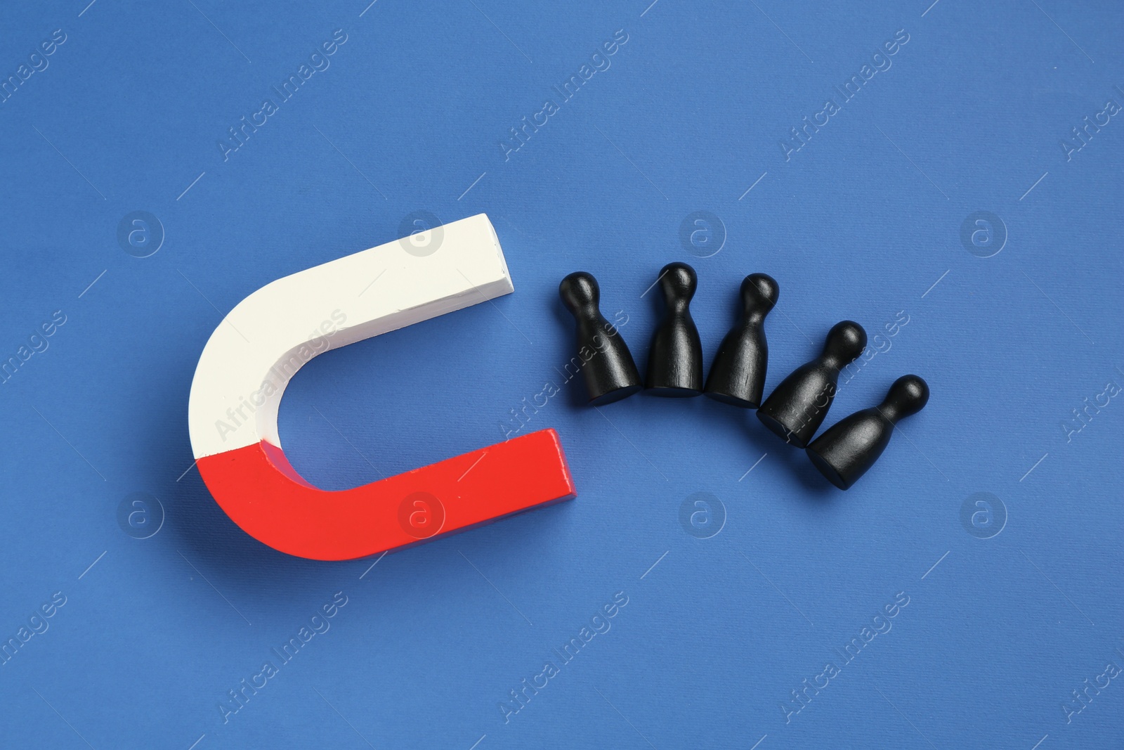 Photo of Magnet attracting human figures on blue background, flat lay