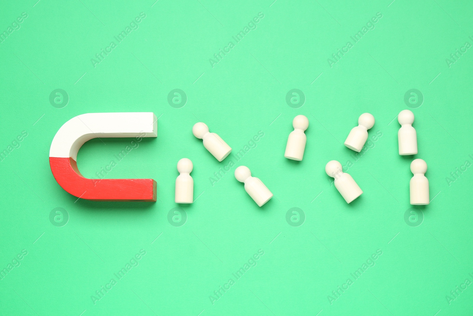 Photo of Magnet attracting human figures on green background, flat lay