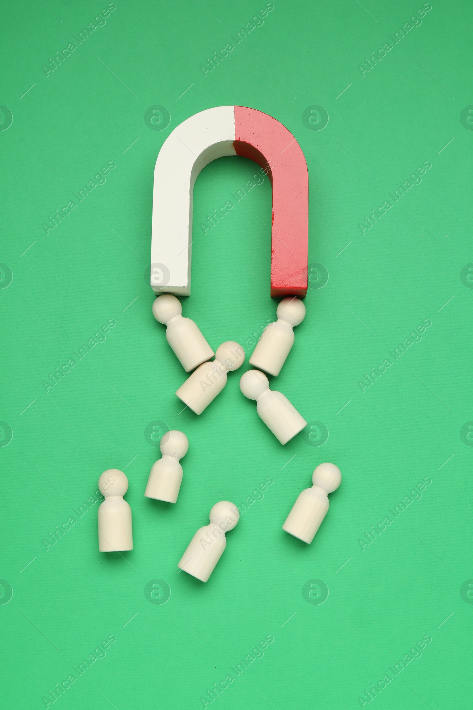 Photo of Magnet attracting human figures on green background, flat lay