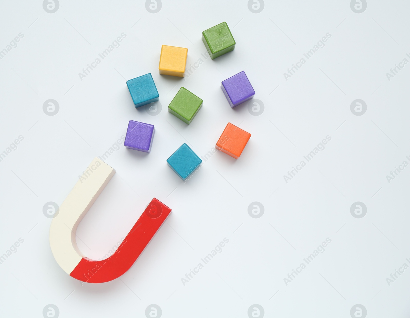 Photo of Magnet attracting colorful cubes on white background, flat lay