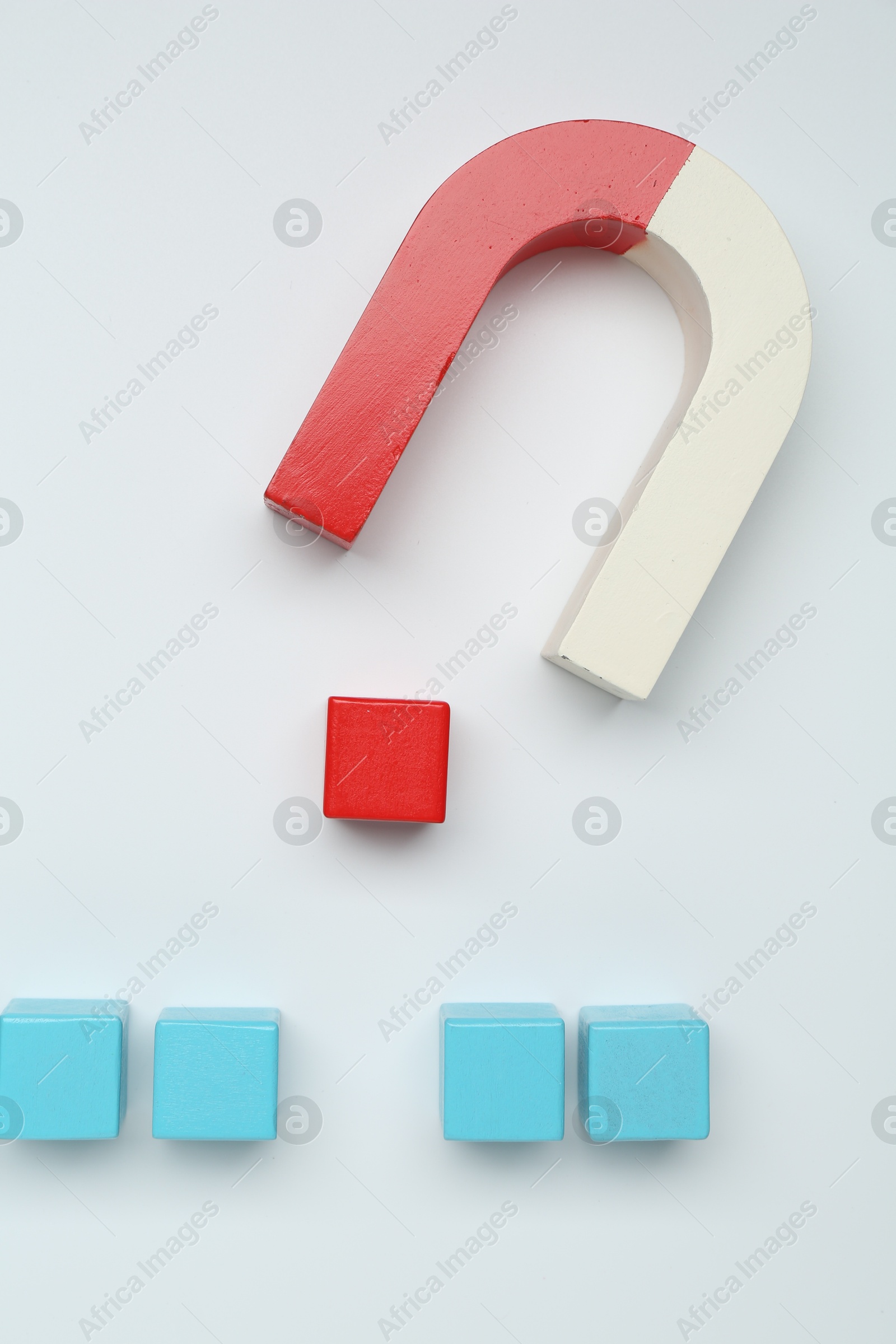 Photo of Magnet attracting colorful cubes on white background, flat lay