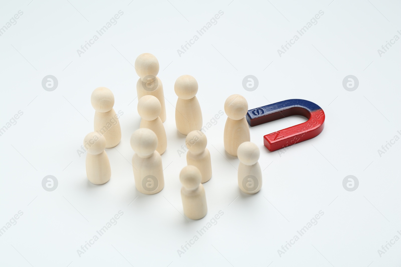 Photo of Magnet attracting human figures on white background, closeup