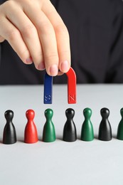 Photo of Woman with magnet attracting different game pieces at white table, closeup