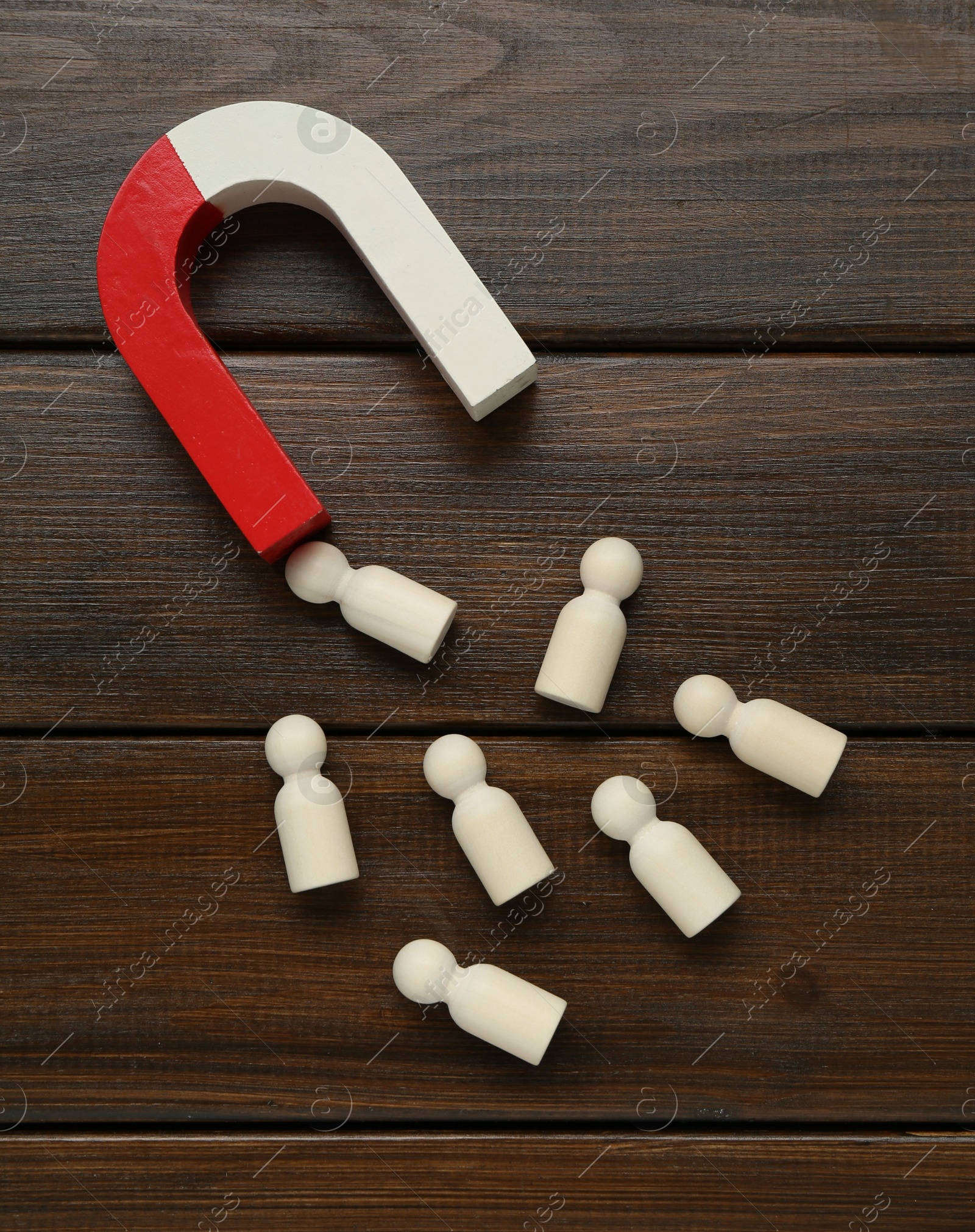 Photo of Magnet attracting human figures on wooden table, flat lay