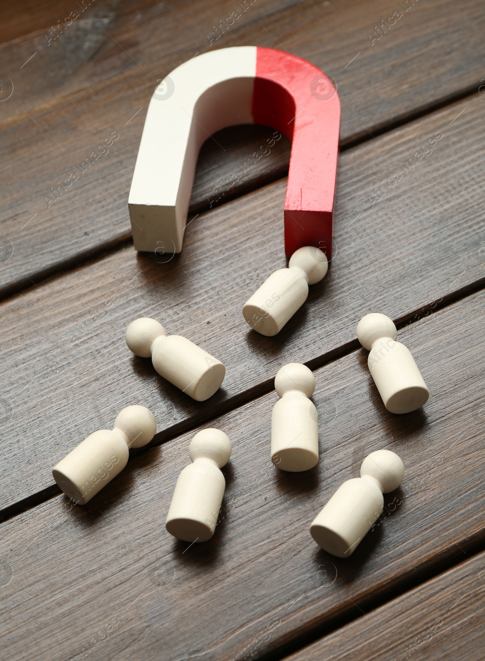 Photo of Magnet attracting human figures on wooden table