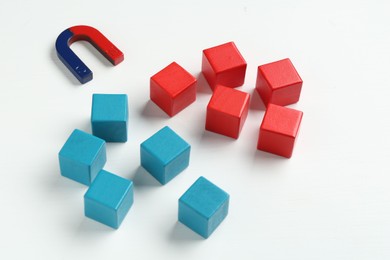 Photo of Magnet attracting colorful cubes on white background