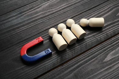 Photo of Magnet attracting human figures on black wooden table