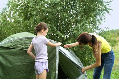 Mother and her daughter setting up camping tent outdoors