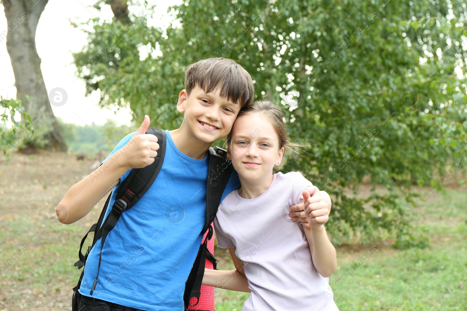 Photo of Cute kids showing peace thumbs up outdoors. Camping season