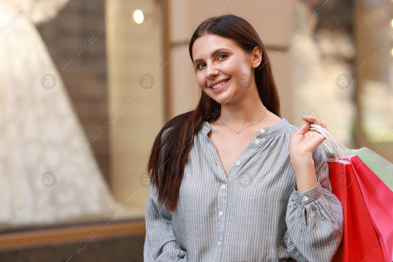 Photo of Happy woman with colorful shopping bags outdoors, space for text