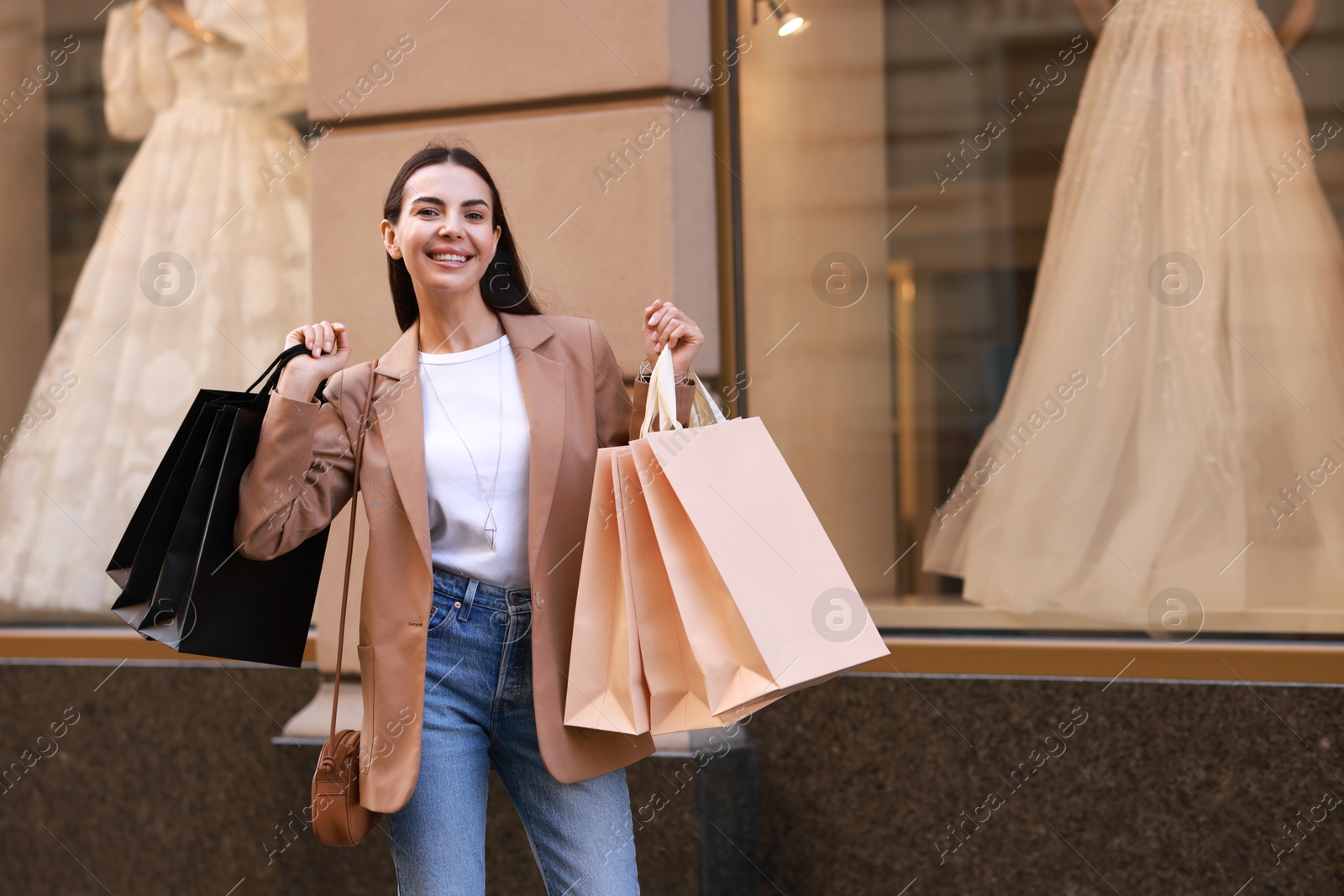 Photo of Happy woman with many shopping bags outdoors, space for text