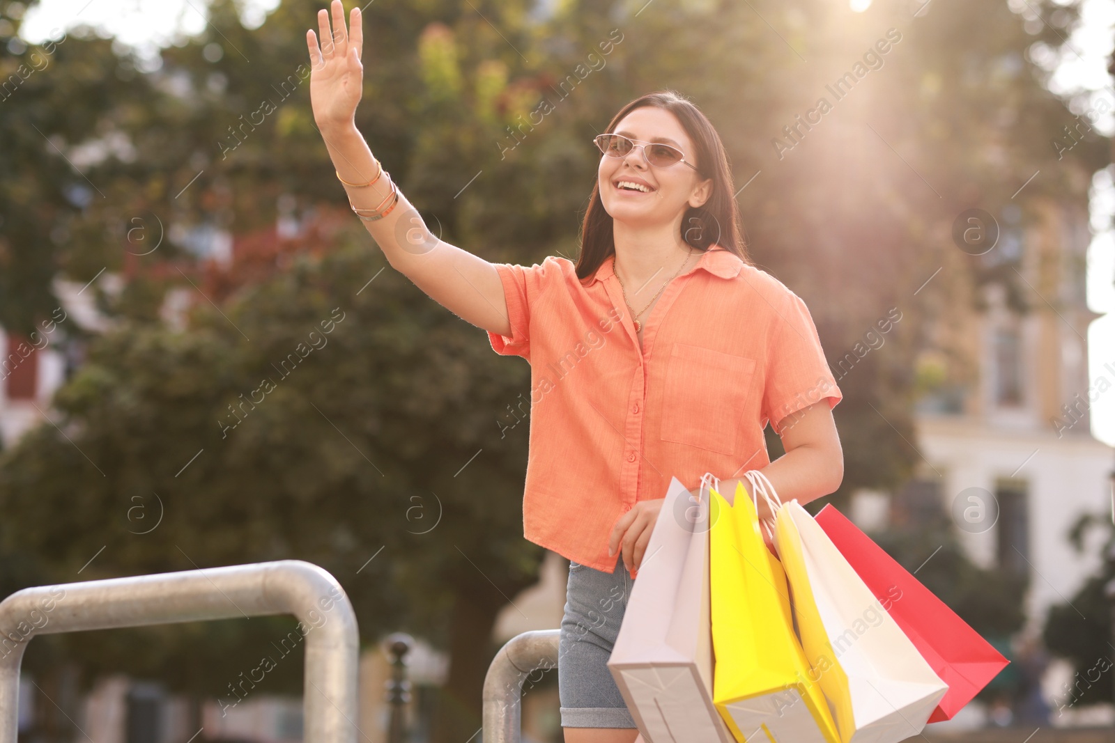 Photo of Happy woman with colorful shopping bags outdoors