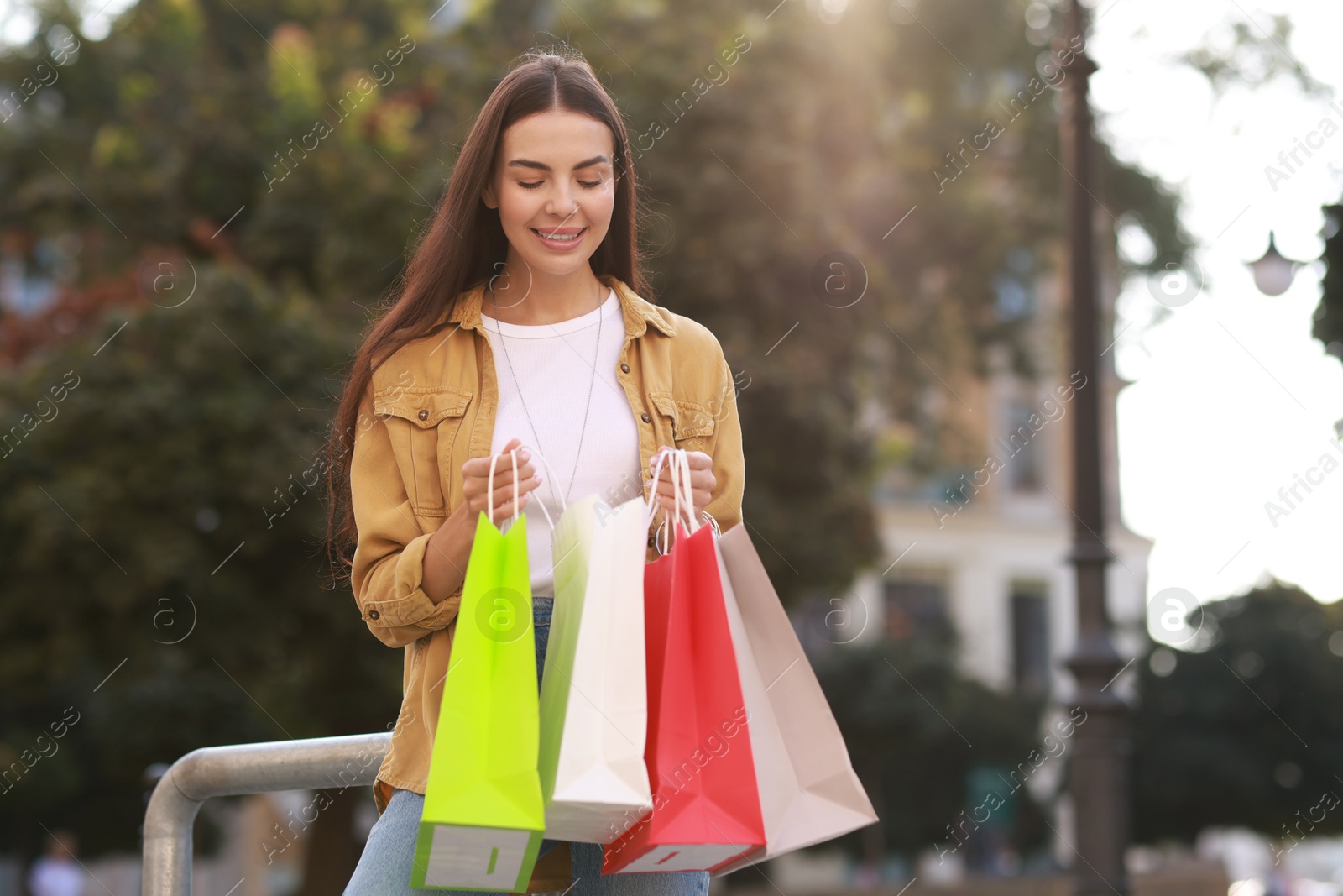 Photo of Happy woman with colorful shopping bags outdoors