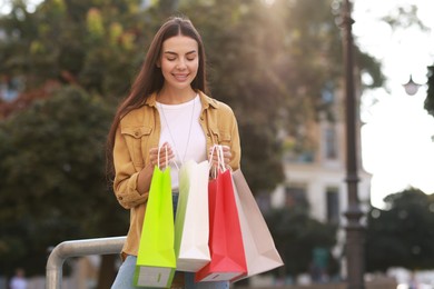 Happy woman with colorful shopping bags outdoors