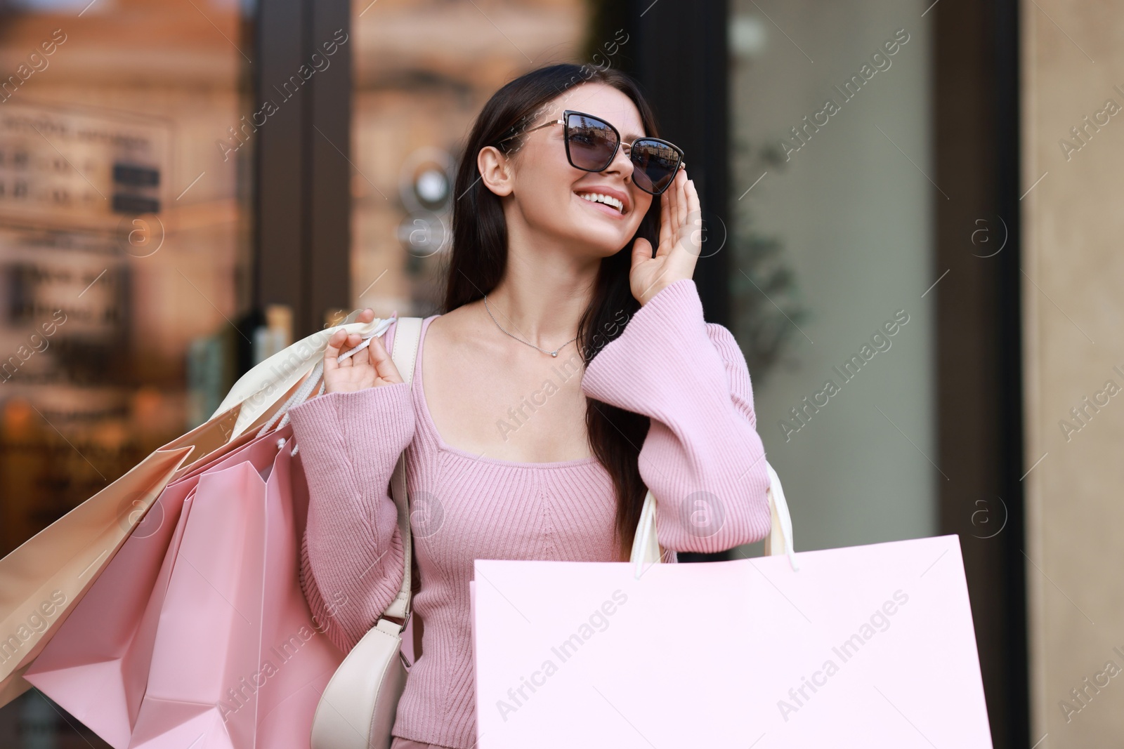 Photo of Happy woman with colorful shopping bags outdoors