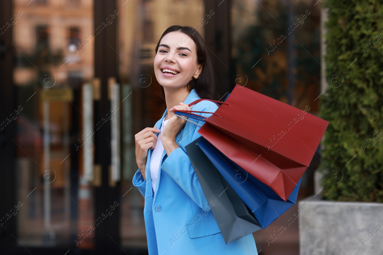 Photo of Happy woman with colorful shopping bags outdoors