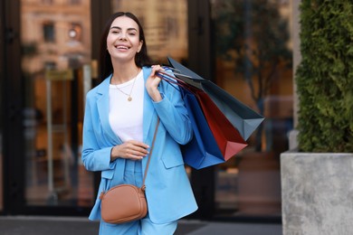 Happy woman with colorful shopping bags outdoors