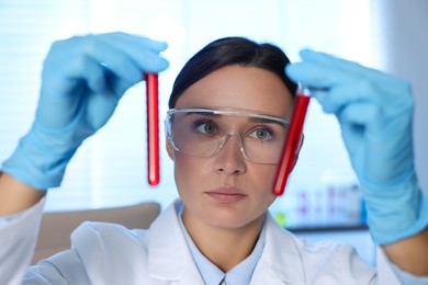 Photo of Laboratory testing. Doctor holding test tubes with blood samples indoors