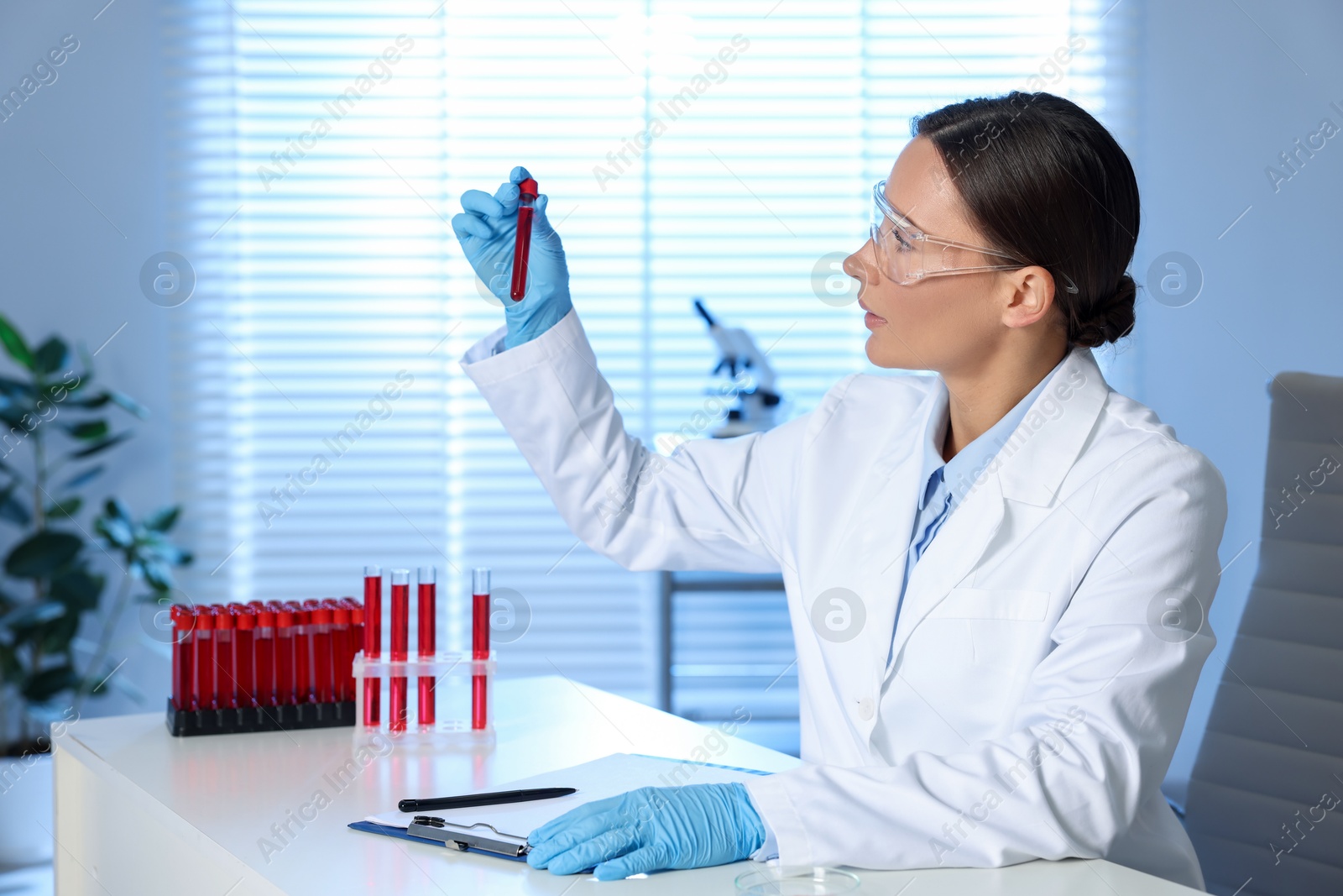 Photo of Laboratory testing. Doctor holding test tube with blood sample at table indoors