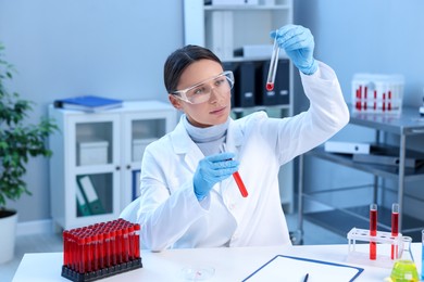 Photo of Laboratory testing. Doctor holding test tubes with blood samples at table indoors