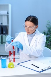 Photo of Laboratory testing. Doctor taking test tube with blood sample at table indoors