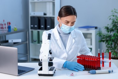 Laboratory testing. Doctor with blood samples in tubes at table indoors