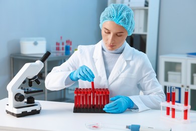 Photo of Laboratory testing. Doctor taking test tube with blood sample at table indoors