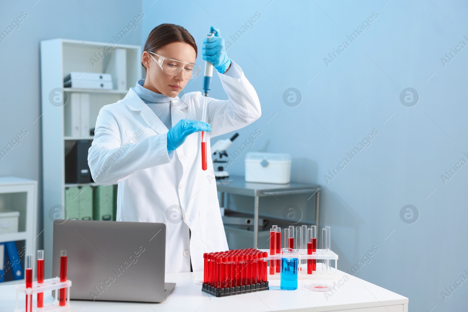 Photo of Laboratory testing. Doctor dripping blood sample into test tube indoors