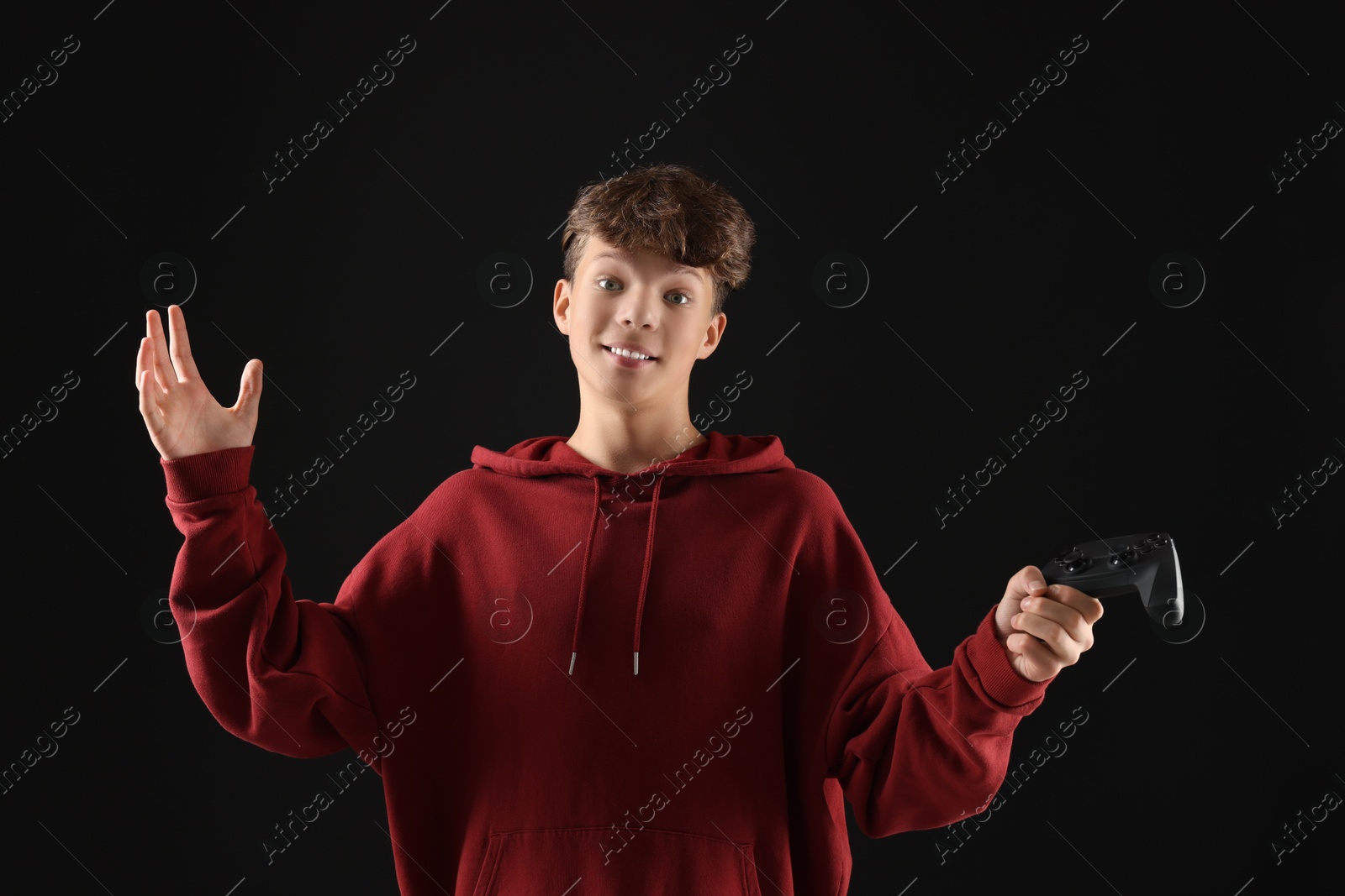 Photo of Happy teenage boy with controller on black background