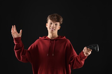 Happy teenage boy with controller on black background