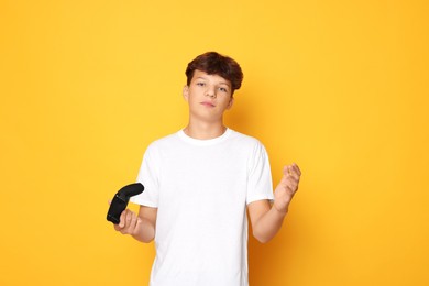 Teenage boy with controller on orange background