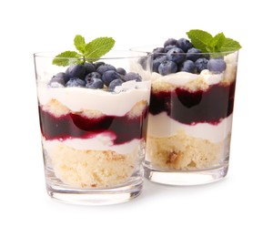 Photo of Tasty trifle dessert. Sponge cake, blueberries, jam and whipped cream in glasses isolated on white